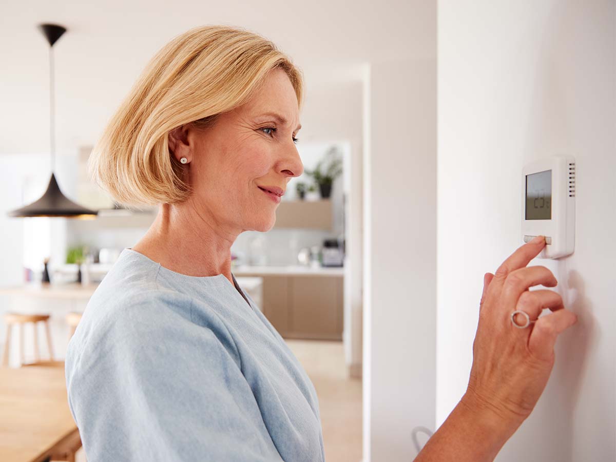 woman adjusting thermostat