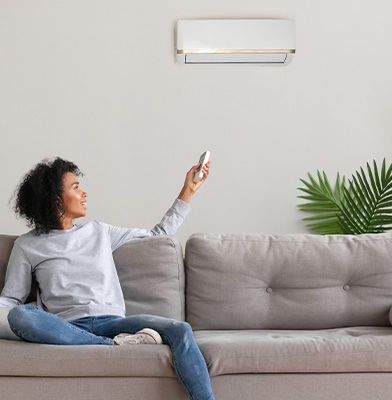 person turning on their AC from the couch with a remote