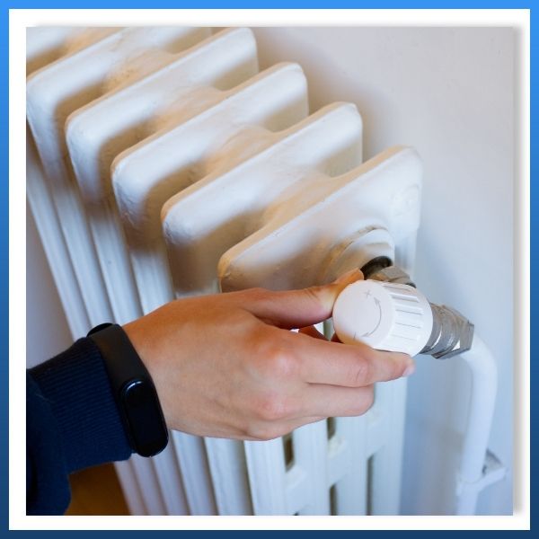 a person adjusting the temperature on a radiator