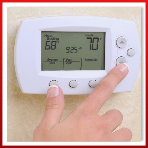 a person adjusting a thermostat